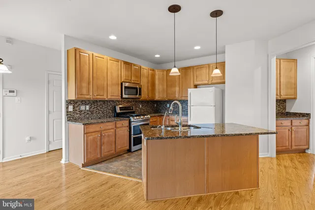 a kitchen with stainless steel appliances granite countertop a sink a stove and a refrigerator