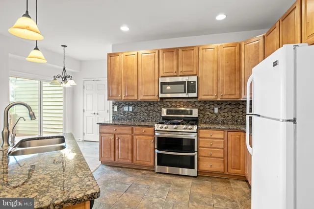 a kitchen with stainless steel appliances granite countertop a stove a sink dishwasher a refrigerator and a microwave