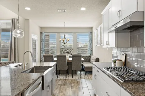a kitchen with stainless steel appliances granite countertop a sink stove and cabinets