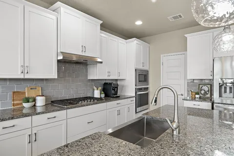 a kitchen with stainless steel appliances granite countertop a sink a stove and cabinets