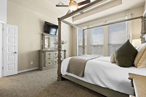 a bedroom with a bed a flat screen tv and windows