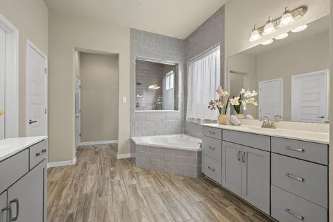 a spacious bathroom with a double vanity sink a mirror and a bathtub