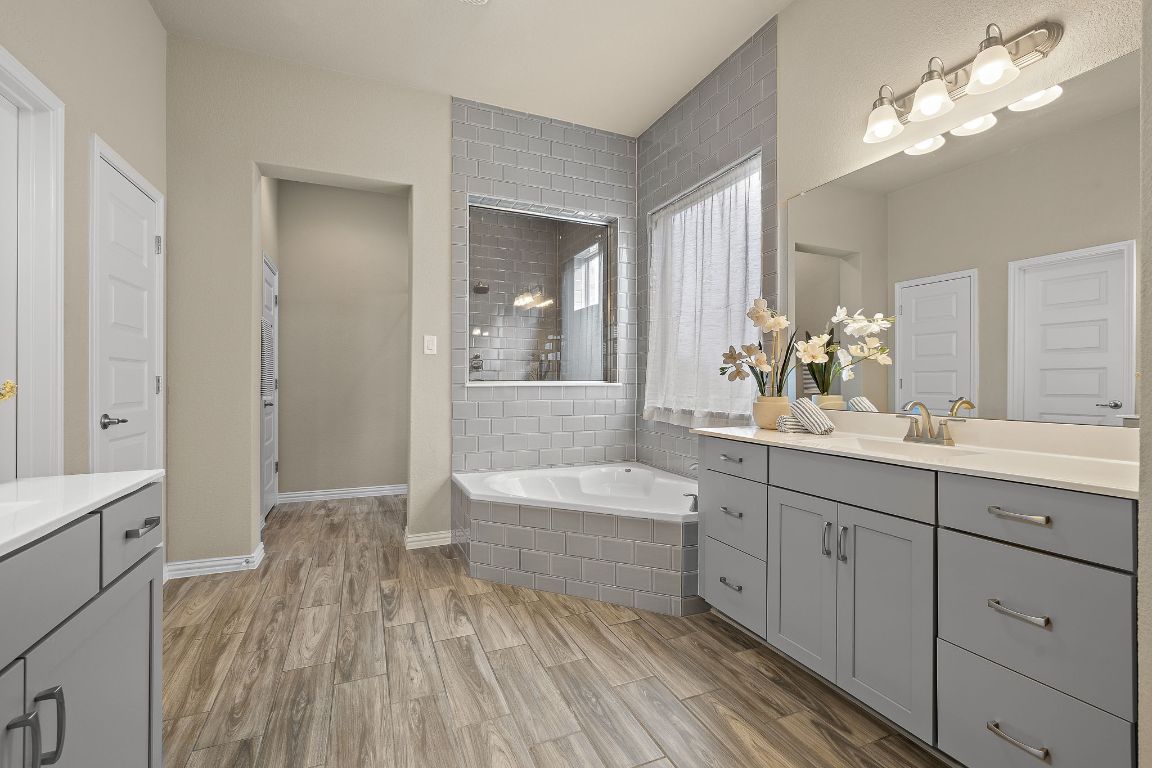 504 Leon Loop Liberty Hill, TX 78642 - Photo 18 of 40 a spacious bathroom with a double vanity sink a mirror and a bathtub