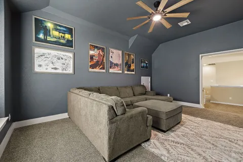 a living room with couches and ceiling fan