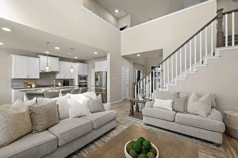a living room with furniture kitchen view and a chandelier