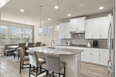 a kitchen with kitchen island granite countertop a table chairs sink and cabinets