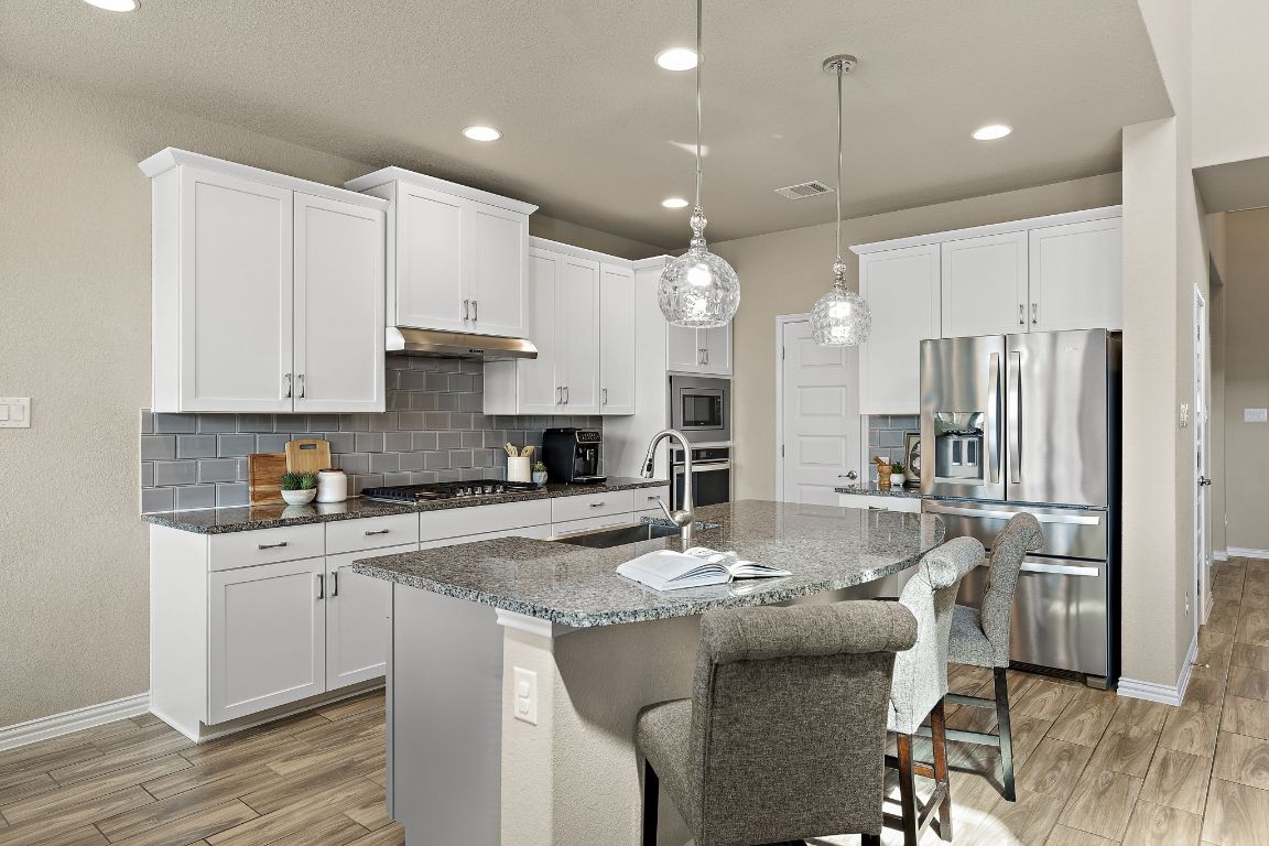 504 Leon Loop Liberty Hill, TX 78642 - Photo 10 of 40 a kitchen with stainless steel appliances granite countertop a sink refrigerator and cabinets