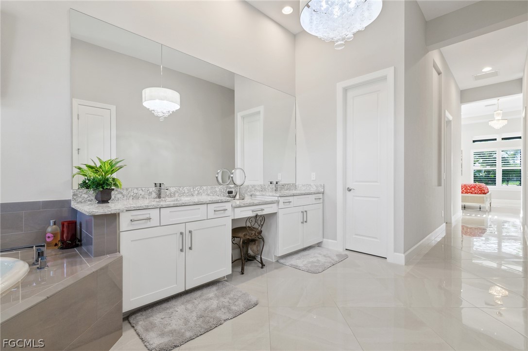 9345 Tulipano Terrace Naples, FL 34119 - Photo 20 of 50 a spacious en suite bathroom with a granite countertop sink and a mirror