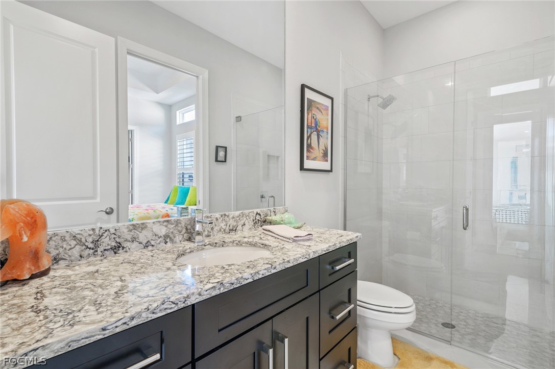 9345 Tulipano Terrace Naples, FL 34119 - Photo 23 of 50 a bathroom with a granite countertop sink a toilet and shower