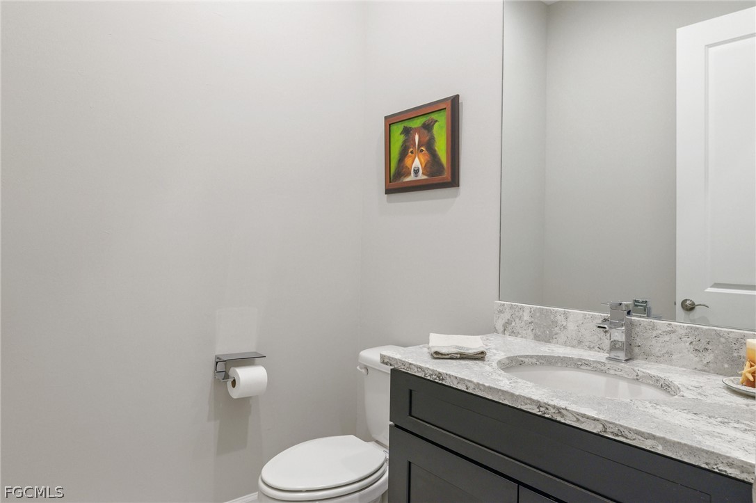 9345 Tulipano Terrace Naples, FL 34119 - Photo 27 of 50 a bathroom with a granite countertop toilet sink and mirror
