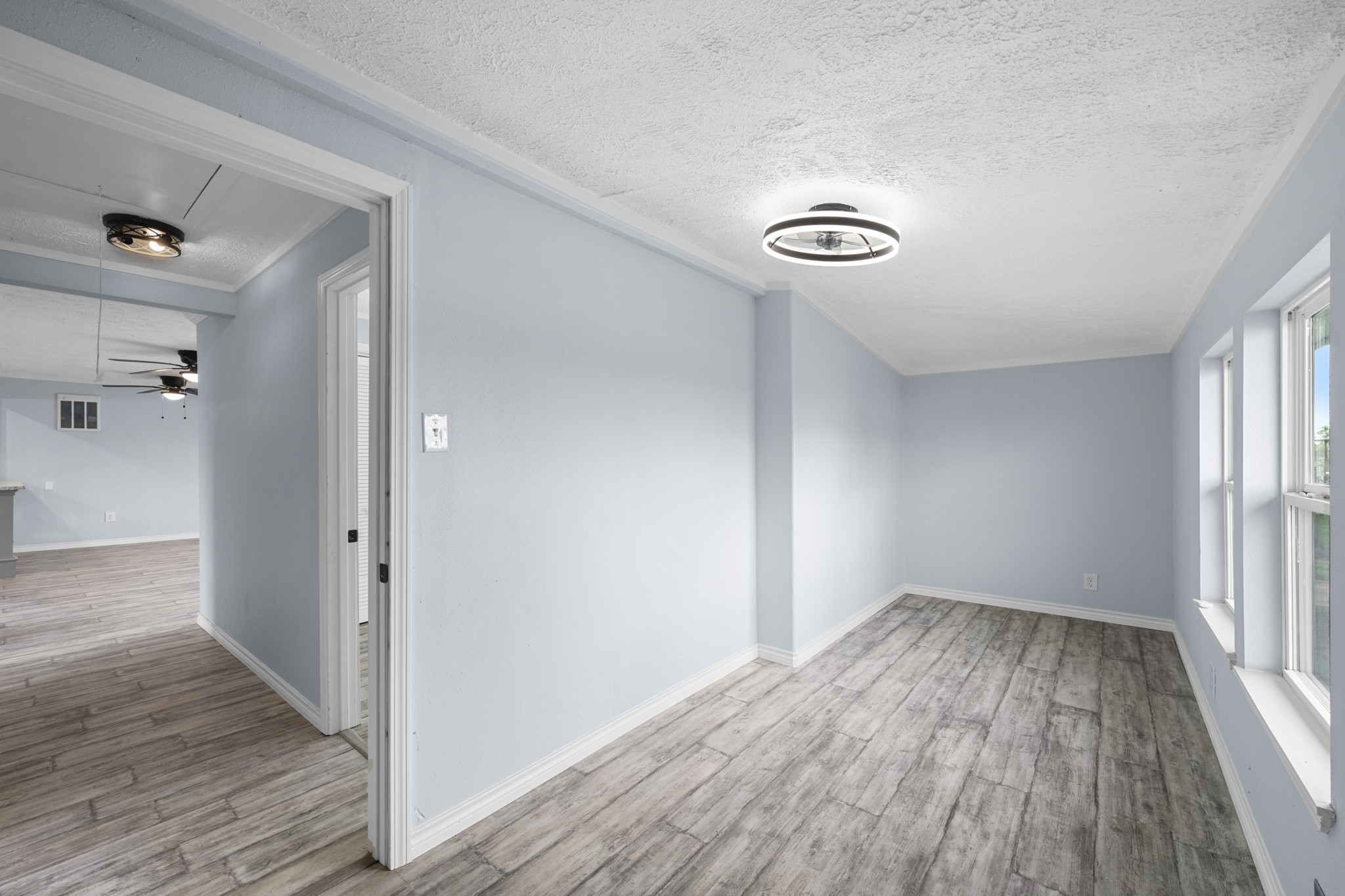 2534 Bastrop Angleton, TX 77515 - Photo 25 of 50 Comfortable secondary bedroom featuring updated wood-look flooring, soft neutral tones, and multiple windows that bring in natural light. The versatile layout offers a bright and inviting space ideal for guests, family, or a home office setup.