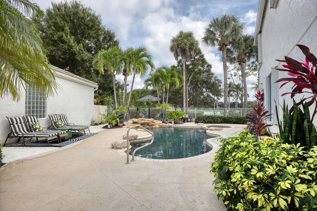 a view of a swimming pool with lounge chair and palm trees