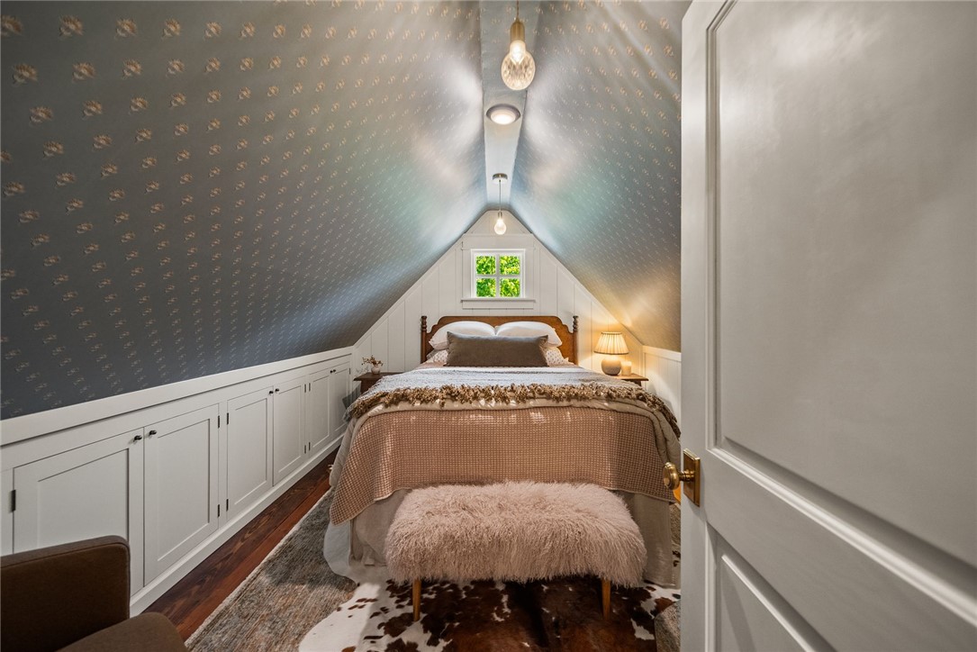 425 Barnhardt Road Timbo, AR 72680 - Photo 52 of 60 Attic room featuring a sloped ceiling with patterned wallpaper, built-in lower cabinetry, hardwood flooring, and a single window