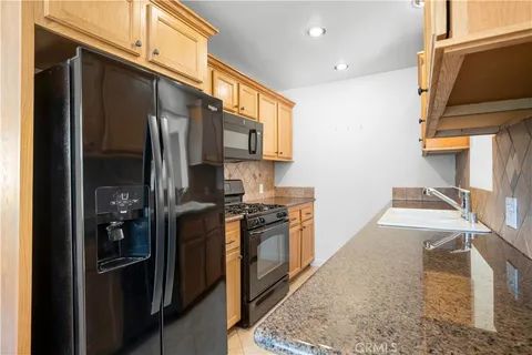 a kitchen with stainless steel appliances granite countertop a refrigerator a stove and a sink with wooden floor