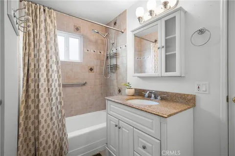 a bathroom with a granite countertop sink a mirror a shower and a bathtub