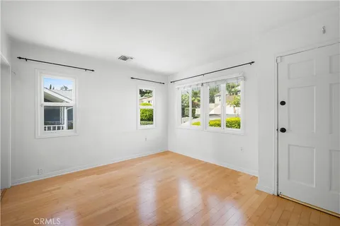 a view of an empty room with a window and wooden floor