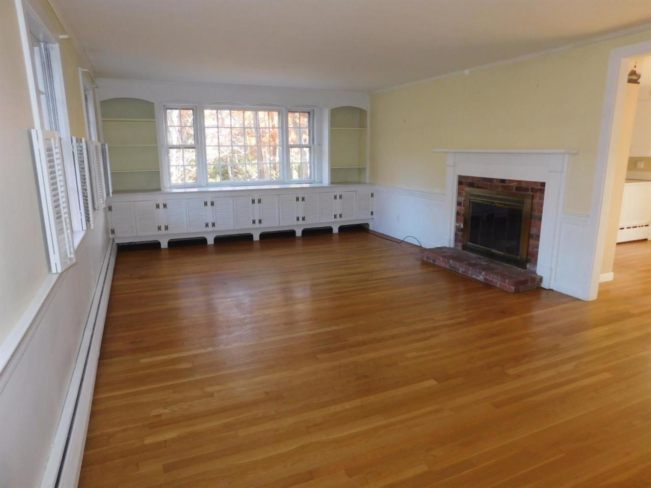 173 Lumbert Mill Road Centerville, MA 02632 - Photo 9 of 17 an empty room with windows fireplace and wooden floor