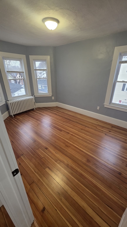 10 Itasca Street, Unit 3 Boston, MA 02126 - Photo 7 of 14 an empty room with wooden floor and windows