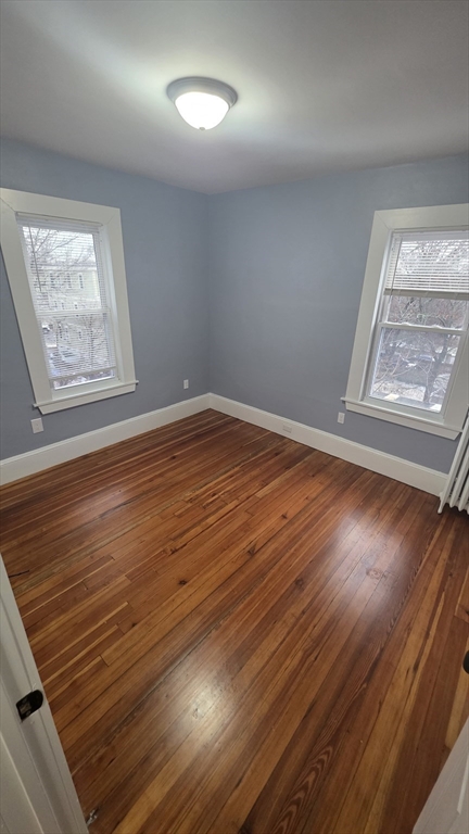 10 Itasca Street, Unit 3 Boston, MA 02126 - Photo 9 of 14 an empty room with wooden floor and windows