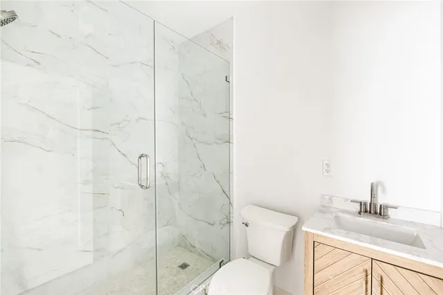 a bathroom with a granite countertop shower a sink and toilet