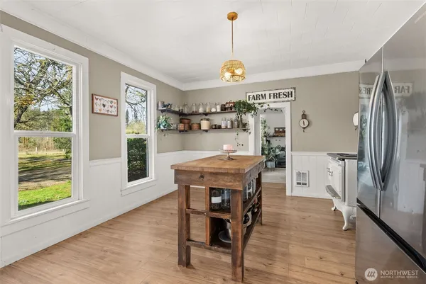 a view of a dining room and livingroom with furniture wooden floor a rug a flat screen tv a painting and a chandelier