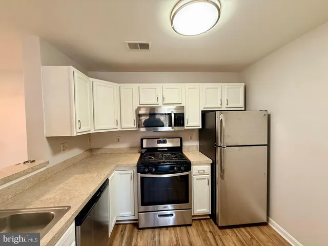 a kitchen with a refrigerator a stove top oven a counter space and cabinets