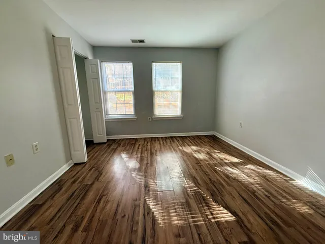 an empty room with wooden floor and windows