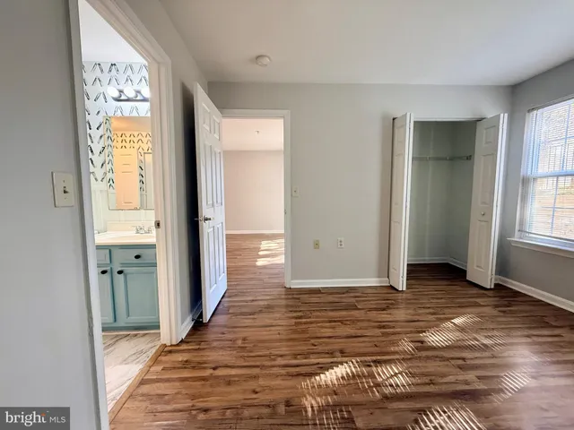 a view of a hallway with wooden floor and a bathroom