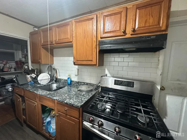 a kitchen with granite countertop a stove sink and cabinets