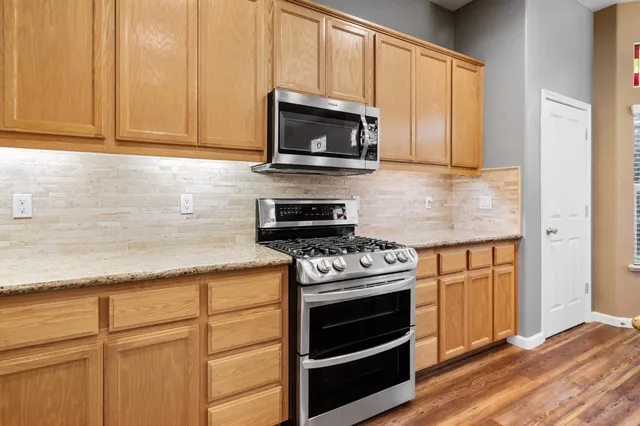 a kitchen with granite countertop cabinets stainless steel appliances and wooden floor