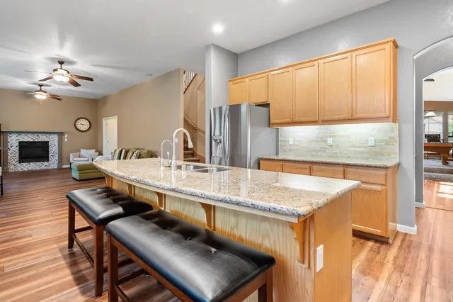 a dining hall with stainless steel appliances granite countertop a kitchen island a stove a sink a dining table and chairs with wooden floor