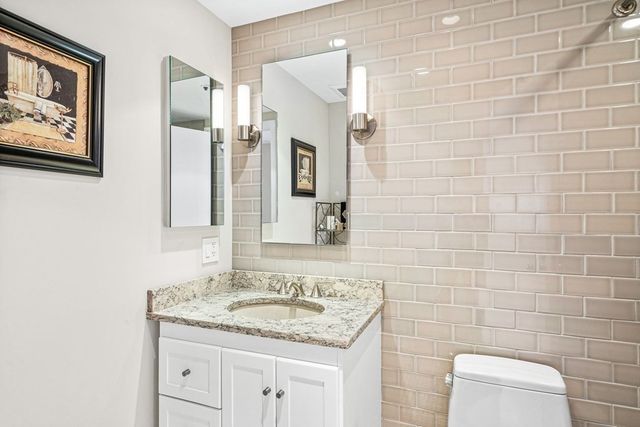 a bathroom with a granite countertop sink a toilet and a mirror
