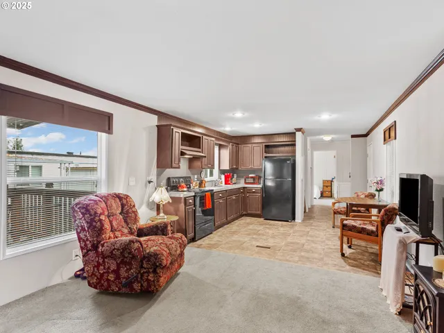 a living room with furniture a flat screen tv and a refrigerator