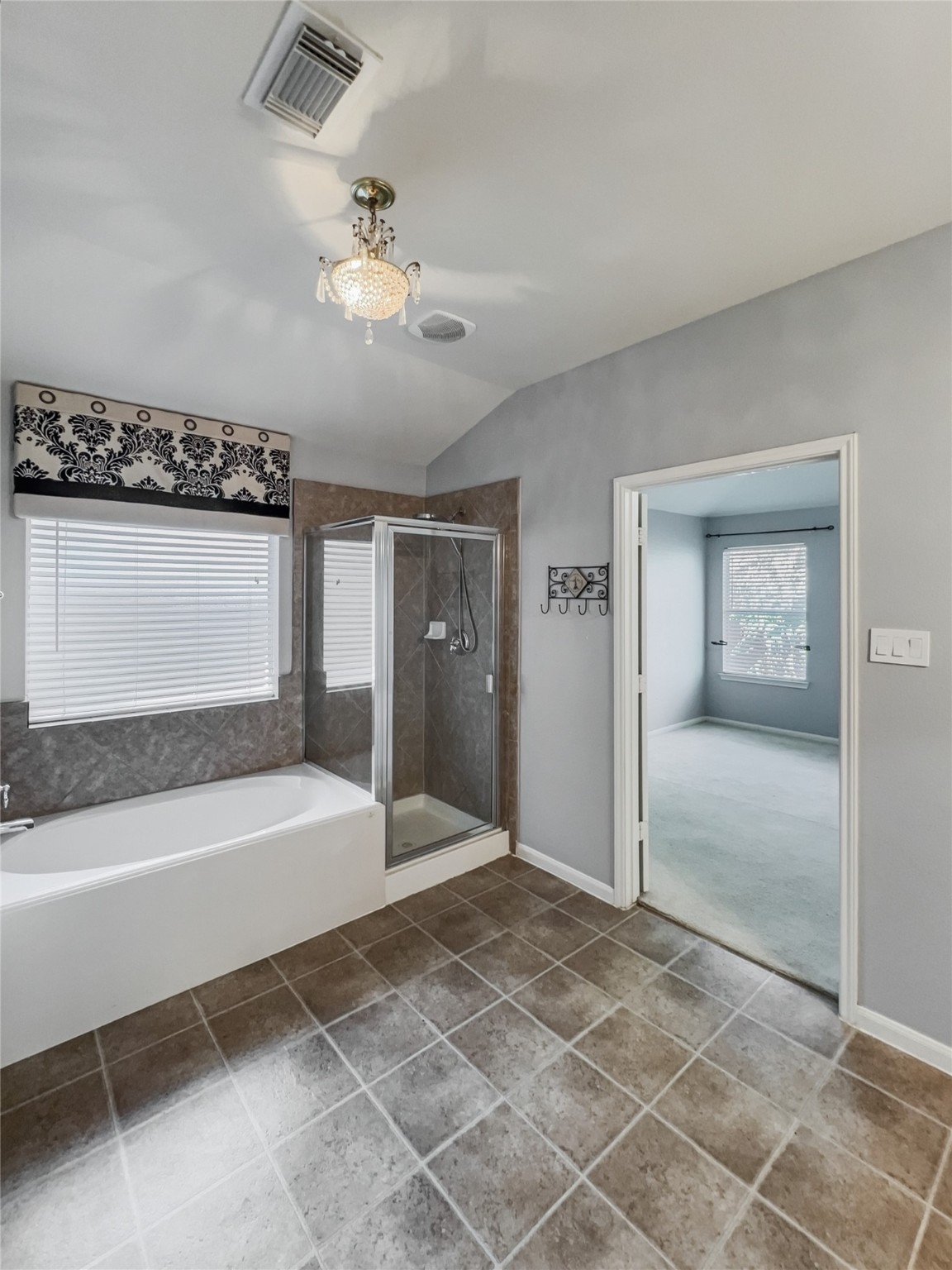 20326 Linshire Drive Spring, TX 77388 - Photo 12 of 24 The primary en-suite features a modern design with a glass-enclosed shower and a separate bathtub. The window is framed by a custom-made bolster & completed with a a chandelier.