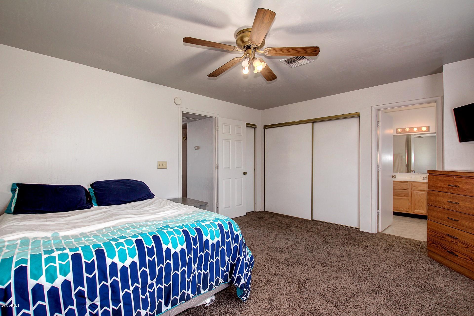 2455 East Broadway Road, Unit 93 Mesa, AZ 85204 - Photo 20 of 26 a bedroom with a bed and a chandelier