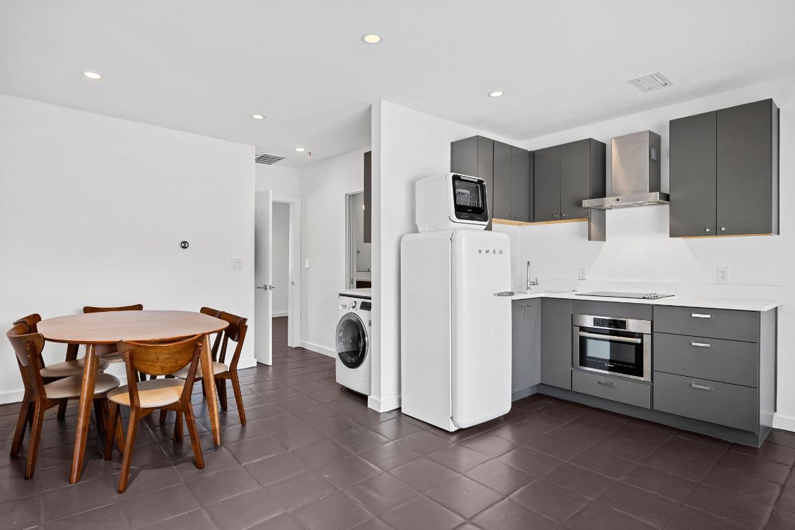 a large kitchen with stainless steel appliances kitchen island granite countertop a stove a sink a refrigerator and a dining table with white cabinets