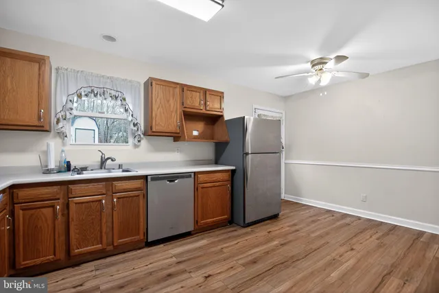 a kitchen with stainless steel appliances granite countertop a sink a stove a refrigerator cabinets and wooden floor