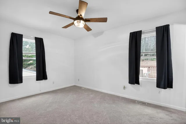 an empty room with windows and fan