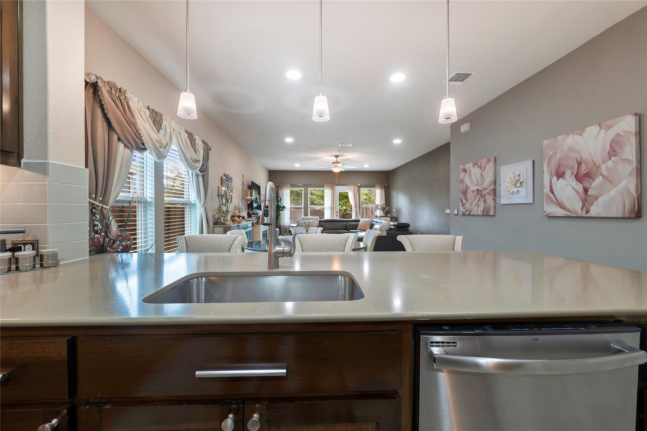 8721 Sikes Way Austin, TX 78747 - Photo 10 of 33 Kitchen island featuring a stainless steel sink with a single-handle faucet, integrated stainless steel dishwasher, and a durable countertop