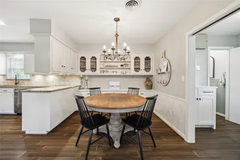 a kitchen with stainless steel appliances a dining table chairs and wooden floor