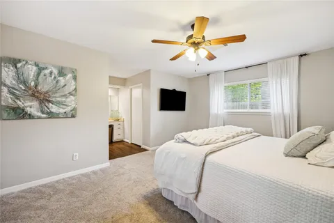 a bedroom with a large bed a flat tv screen and a chandelier