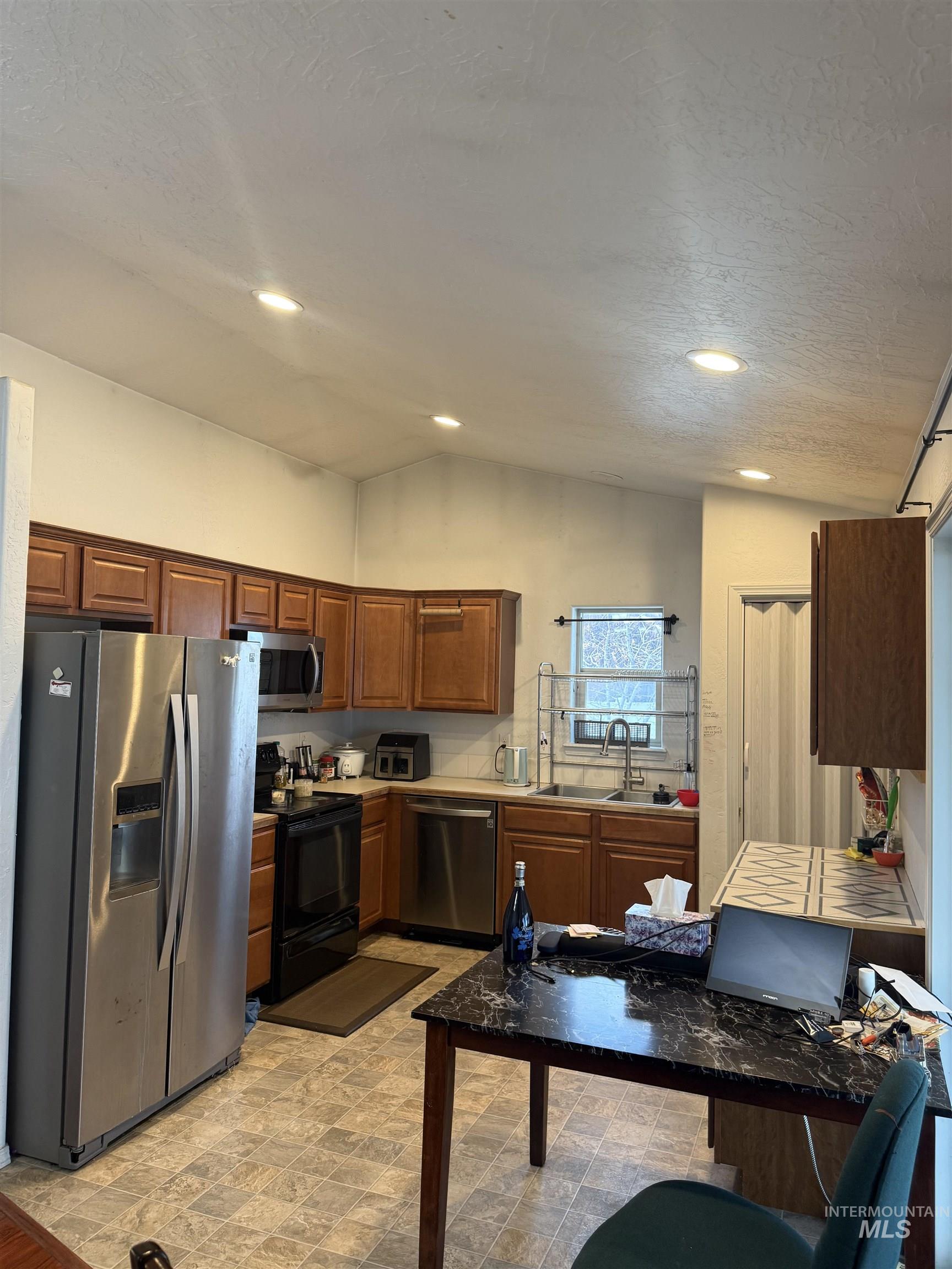 494 Adria Lane Twin Falls, ID 83301 - Photo 11 of 19 Kitchen with stainless steel appliances, vaulted ceiling, brown cabinetry, a textured ceiling, and recessed lighting