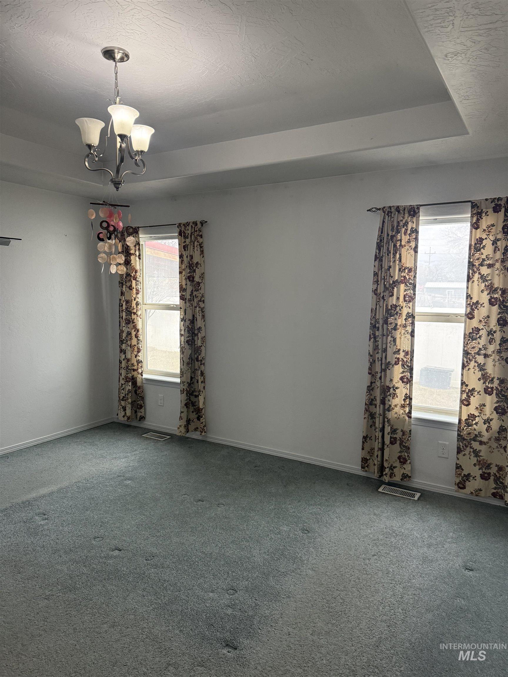 494 Adria Lane Twin Falls, ID 83301 - Photo 12 of 19 Carpeted spare room with a tray ceiling, a chandelier, and a textured ceiling