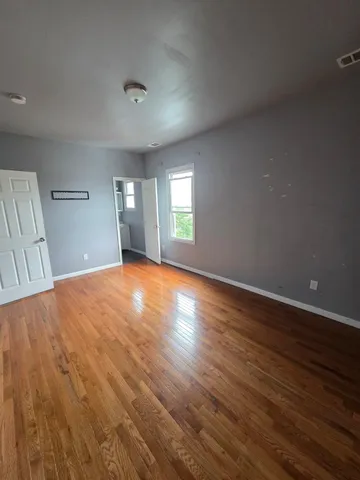 a view of a big room with wooden floor and windows