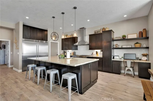 a kitchen with stainless steel appliances kitchen island granite countertop a sink refrigerator and cabinets