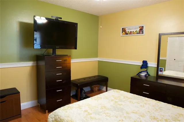 a bedroom with a bed and a flat tv screen on dresser