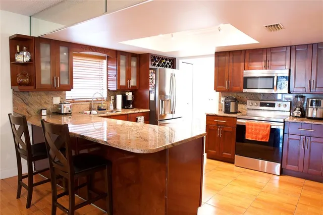 a kitchen with stainless steel appliances kitchen island granite countertop a sink dishwasher a stove a refrigerator with a dining table and chairs