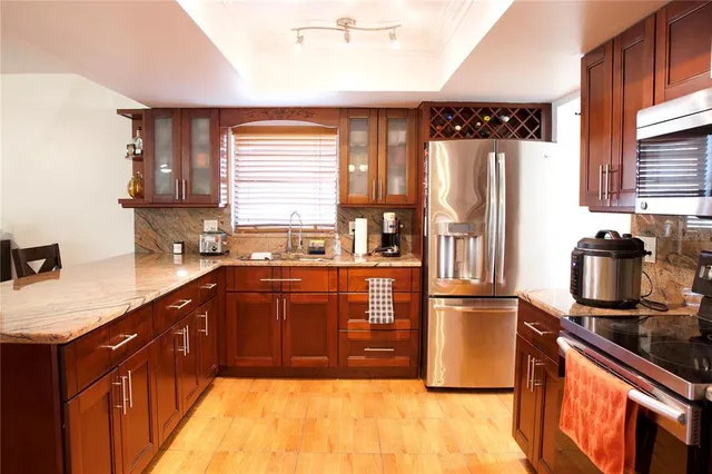 a kitchen with stainless steel appliances granite countertop a refrigerator a sink a stove wooden cabinets and a dining table