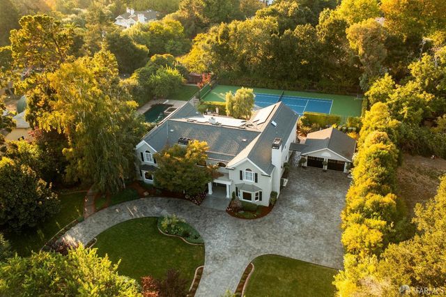 an aerial view of a house with swimming pool and large trees