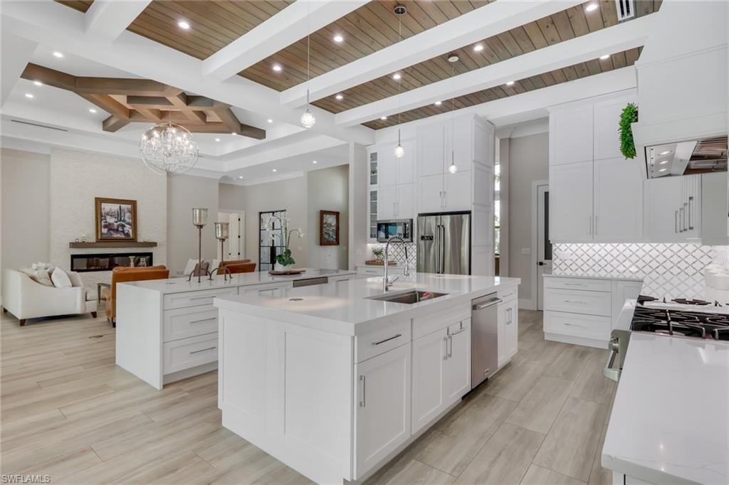 530 1st Street Northwest Naples, FL 34120 - Photo 12 of 35 a large white kitchen with kitchen island white cabinets and stainless steel appliances